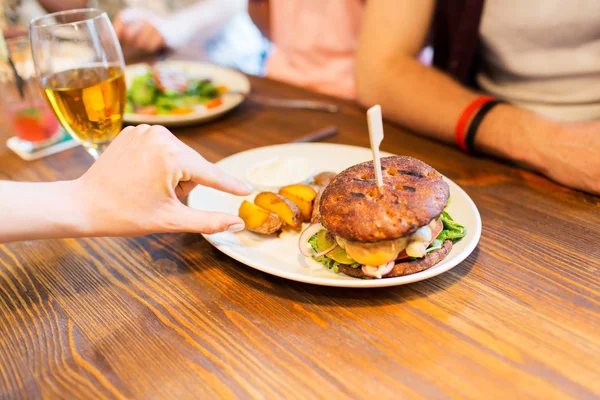 Крупним планом друзі руки діляться бургер в барі — стокове фото
