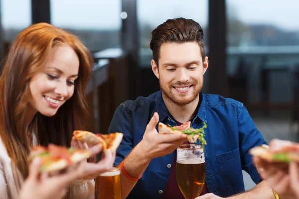 Vrienden eten pizza met bier in restaurant — Stockfoto