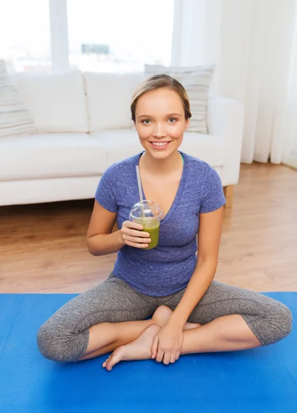 Šťastná žena s smoothie sedí na mat doma — Stock fotografie