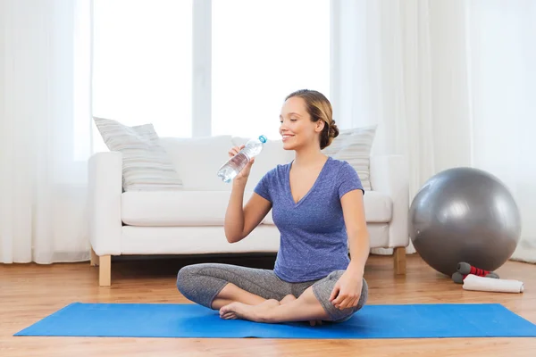 Mujer feliz con botella de agua haciendo ejercicio en casa — Foto de Stock