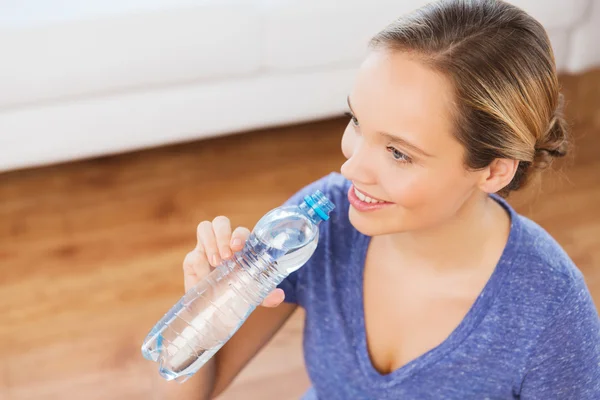 Mulher feliz com garrafa de água em casa — Fotografia de Stock