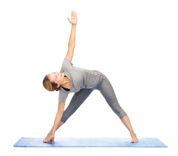 Vrouw maken yoga driehoek pose op de mat — Stockfoto