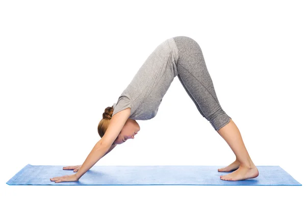 Kadın yapma yoga köpek poz mat — Stok fotoğraf