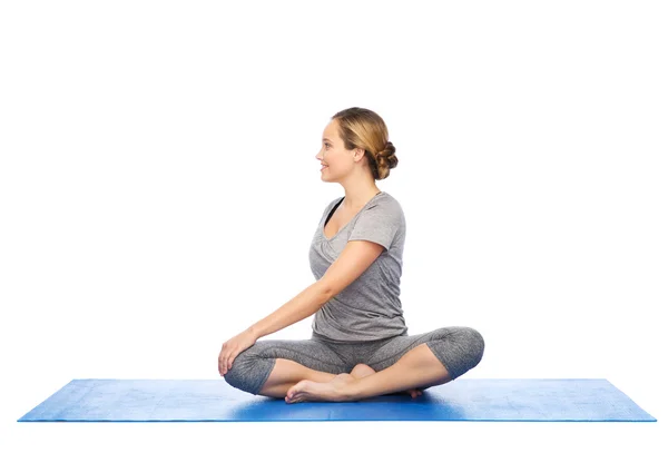 Mujer haciendo yoga en actitud de giro en la estera —  Fotos de Stock