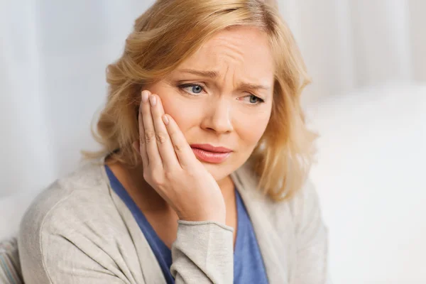 Olycklig kvinna lider tandvärk hemma Stockfoto