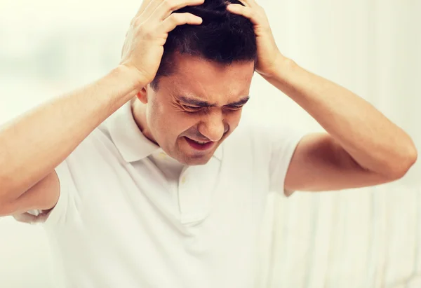 Unhappy man suffering from head ache at home — Stock Photo, Image