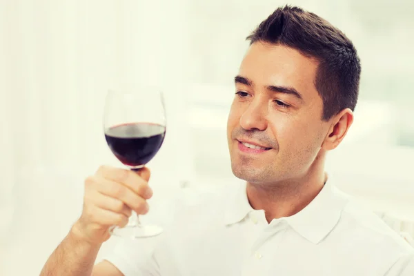 Homem feliz bebendo vinho tinto de vidro em casa — Fotografia de Stock