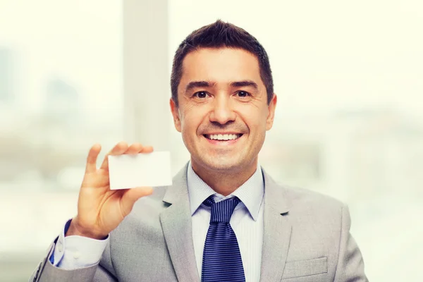Smiling businessman in suit showing visiting card — Stock fotografie