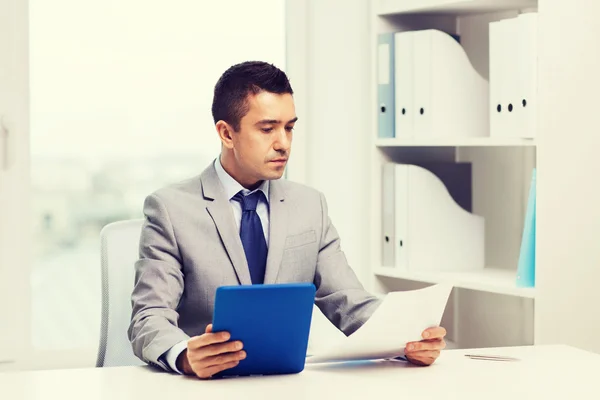 Uomo d'affari con tablet pc e carte in ufficio — Foto Stock