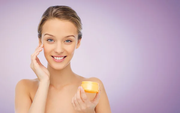 Happy young woman applying cream to her face — Stock Photo, Image