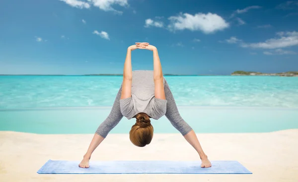 Kvinna att göra yoga framåt böj på stranden — Stockfoto