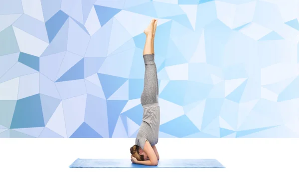 Kvinna som gör yoga i huvudstående pose på matta — Stockfoto
