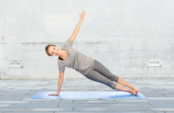 Mujer haciendo yoga en la postura lateral de la tabla en la estera —  Fotos de Stock