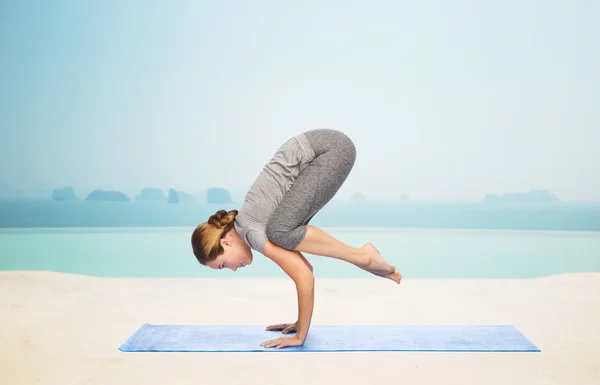 Mujer haciendo yoga en postura de grúa sobre estera —  Fotos de Stock