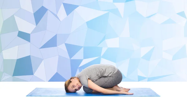 Счастливая женщина делает yoga в положении ребенка на циновке — стоковое фото