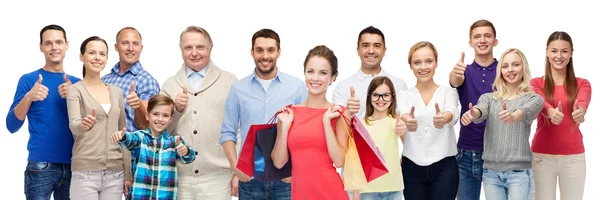 Pessoas felizes com sacos de compras mostrando polegares para cima — Fotografia de Stock