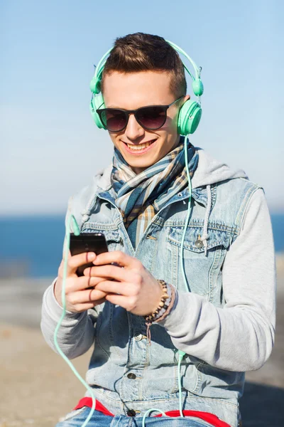 Gelukkig jonge man in hoofdtelefoons met smartphone — Stockfoto