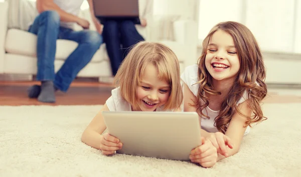 Smiling sister with tablet pc and parents on back — Stock Photo, Image