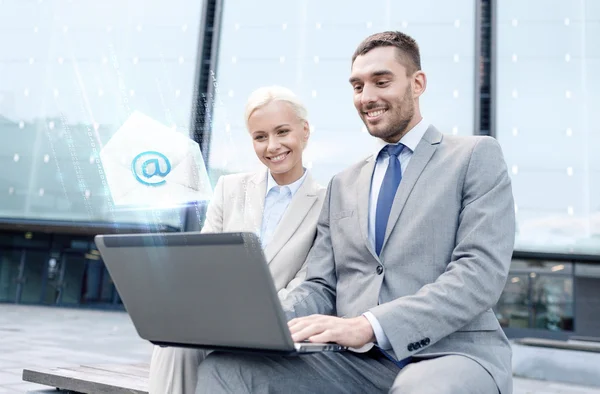 Uomini d'affari sorridenti con laptop invio di e-mail — Foto Stock