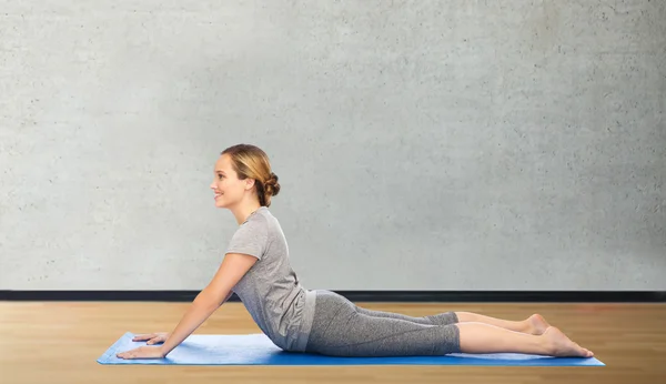 Vrouw maken yoga in hond pose op de mat — Stockfoto