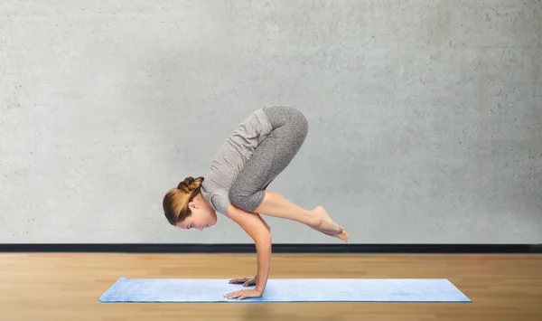 Donna che fa yoga in posa gru sul tappeto — Foto Stock