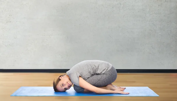 Donna felice fare yoga in posa bambino sul tappeto — Foto Stock