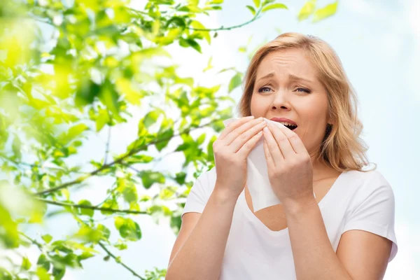 Unhappy woman with paper napkin sneezing — Stok fotoğraf