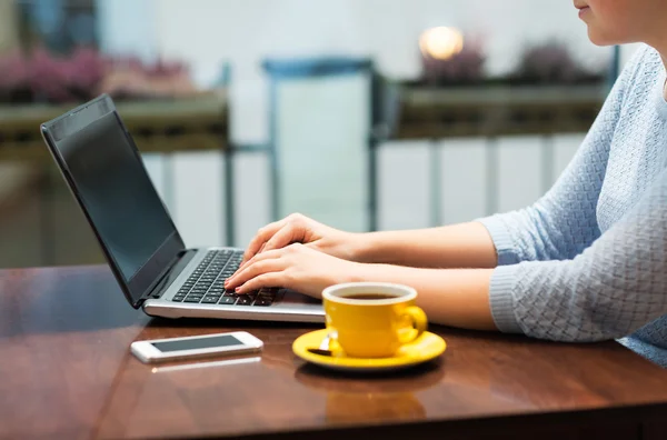 Close up of woman typing on laptop with coffee — Stock Photo, Image