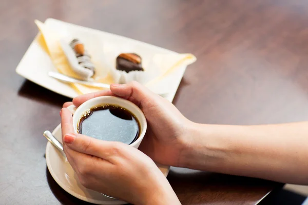 Primer plano de la mujer sosteniendo taza de café y postre — Foto de Stock