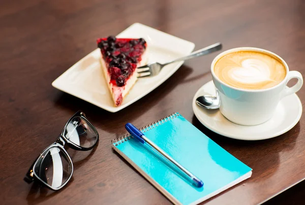 Close-up de notebook com caneta, xícara de café e bolo — Fotografia de Stock