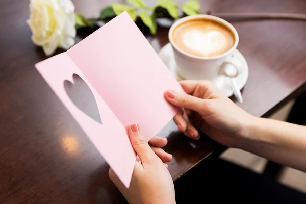 Close up of woman reading greeting card and coffee — Stock Photo, Image