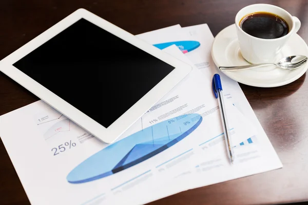 Close up of tablet pc, charts and coffee on table — Stock Photo, Image