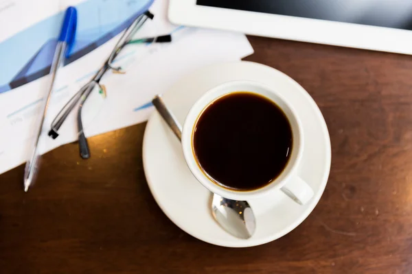 Primer plano de café, gráficos y tableta pc en la mesa — Foto de Stock