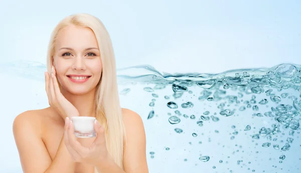 Mujer aplicando crema hidratante en su piel de la cara —  Fotos de Stock