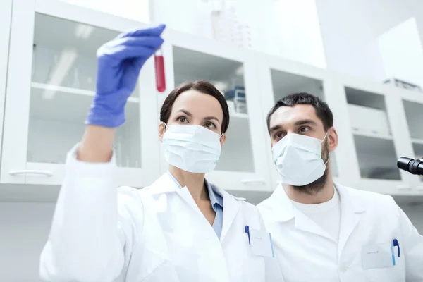 Jóvenes científicos haciendo pruebas o investigaciones en laboratorio — Foto de Stock