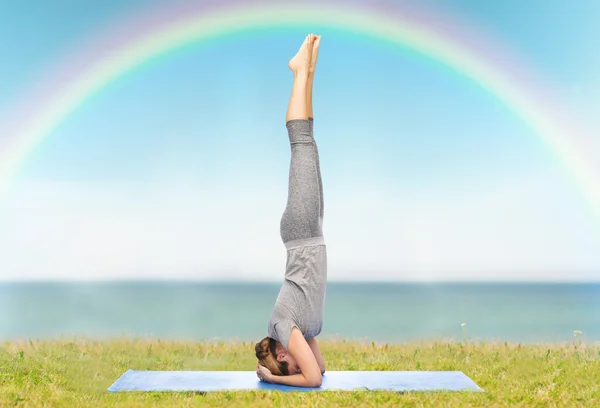 Vrouw maken yoga in headstand pose op mat — Stockfoto