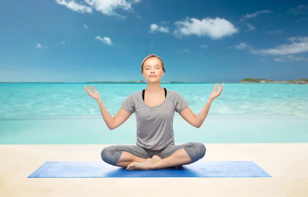 Kvinna att göra yoga meditation i lotus pose på matta — Stockfoto