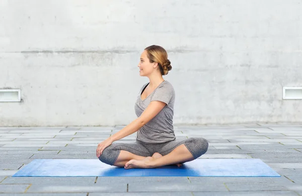 Женщина делает yoga в твист позе на циновке — стоковое фото