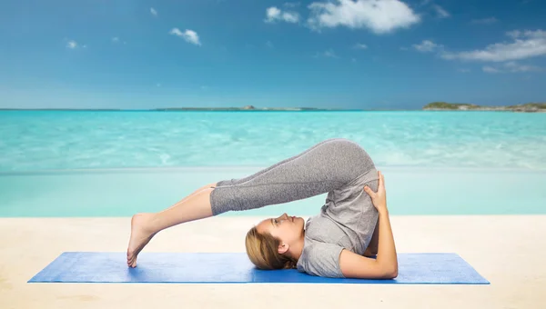 Женщина делает yoga в позе плуга на циновке — стоковое фото