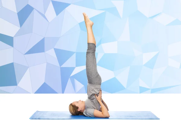 Donna che fa yoga in posa spalla sul tappeto — Foto Stock