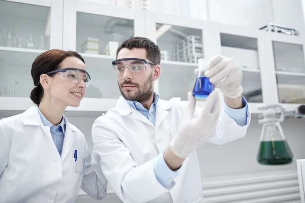 Jóvenes científicos haciendo pruebas o investigaciones en laboratorio — Foto de Stock