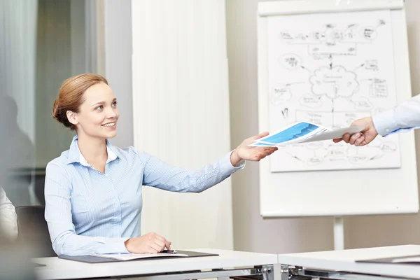 Business woman taking papers from someone in office — стоковое фото