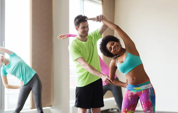 Grupa osób uśmiechający się wyciąganie w siłowni — Zdjęcie stockowe