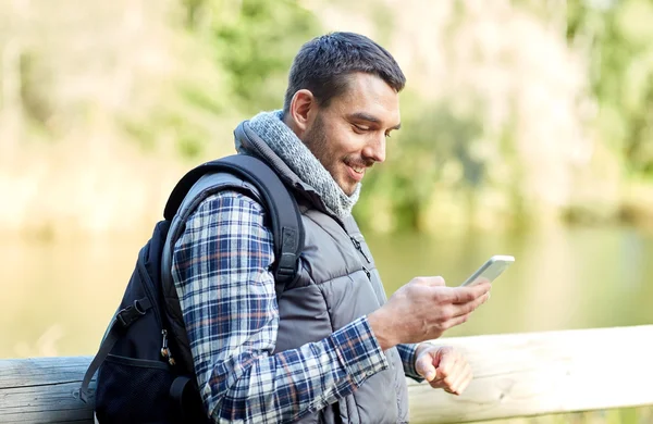 Gelukkig man met rugzak en smartphone outdoors — Stockfoto