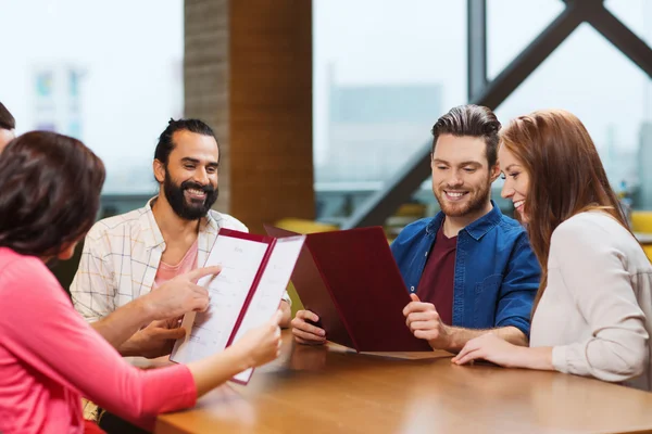 Smiling friends discussing menu at restaurant — Stock Photo, Image