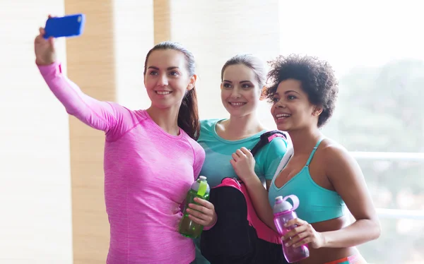 Mujeres felices con smartphone tomando selfie en el gimnasio — Foto de Stock