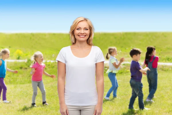 Smiling woman over group of little kids outdoors — Stock Photo, Image