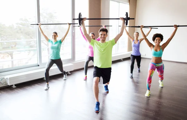 Grupo de personas haciendo ejercicio con bares en el gimnasio — Foto de Stock