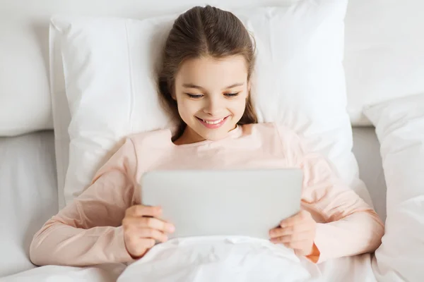 Chica feliz acostada en la cama con la tableta PC en casa —  Fotos de Stock