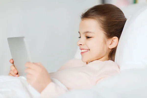 Menina feliz deitado na cama com tablet pc em casa — Fotografia de Stock